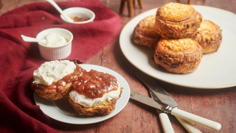 Scones on two plates, one open with goats cheese and fig chutney spread over and more in small pots